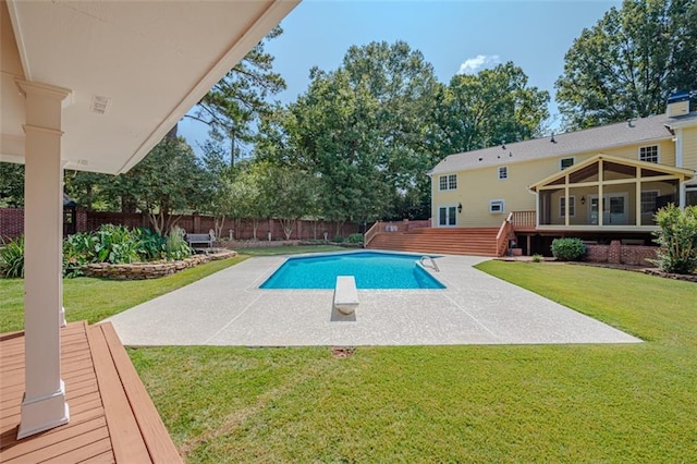 view of pool with a deck, a diving board, a yard, and a patio area