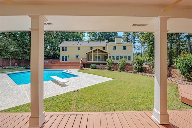 view of swimming pool featuring a sunroom, a wooden deck, a yard, and a diving board