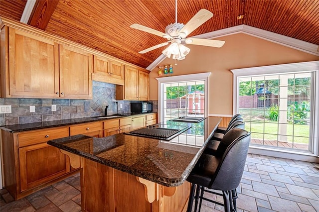 kitchen featuring a wealth of natural light, vaulted ceiling, ceiling fan, and a kitchen bar