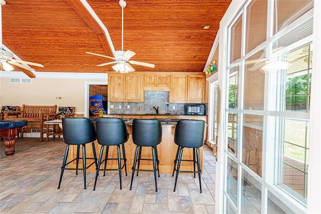 kitchen featuring wooden ceiling, backsplash, light brown cabinetry, and ceiling fan