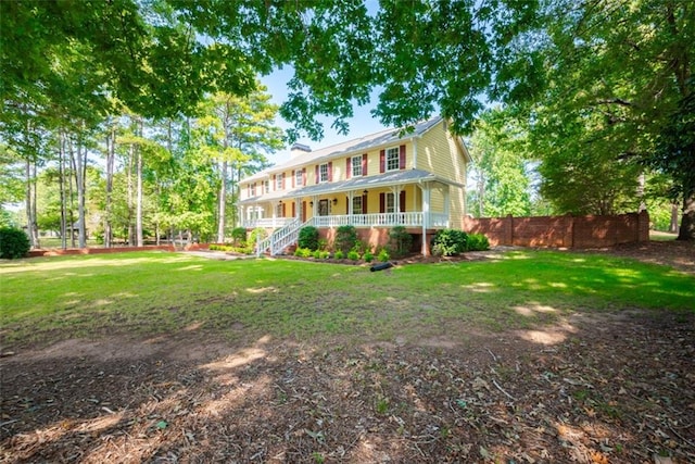 back of property with covered porch and a yard