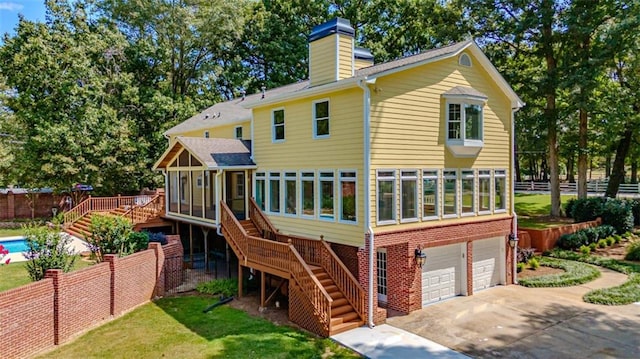 exterior space with a garage, a sunroom, a wooden deck, and a front yard