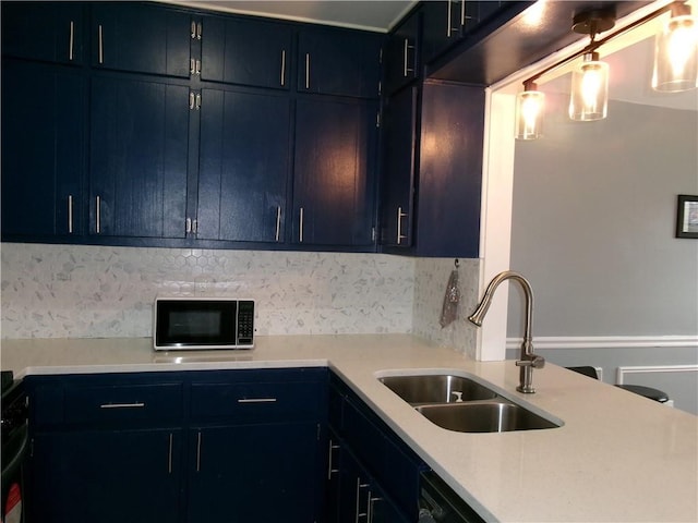 kitchen with blue cabinets, decorative backsplash, light countertops, and a sink