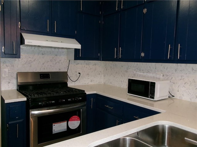 kitchen featuring white microwave, blue cabinetry, gas range, and under cabinet range hood