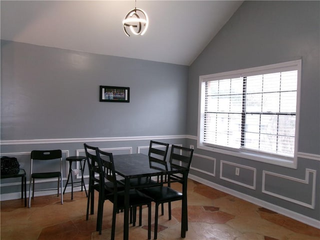 dining room featuring a wainscoted wall, vaulted ceiling, and a decorative wall