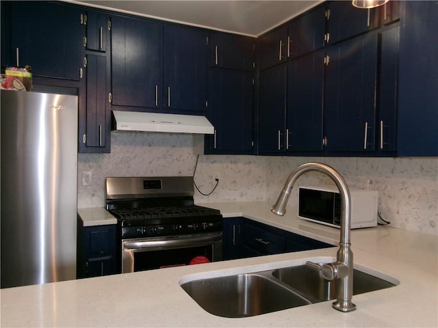 kitchen featuring under cabinet range hood, a sink, light countertops, appliances with stainless steel finishes, and decorative backsplash