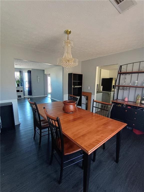 dining area with an inviting chandelier, dark hardwood / wood-style flooring, and a textured ceiling