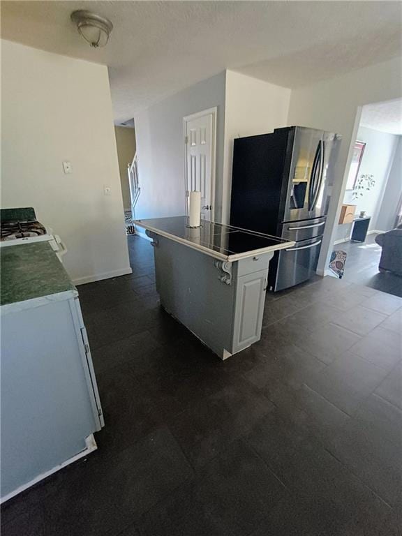 kitchen with white cabinetry, stove, and stainless steel refrigerator with ice dispenser