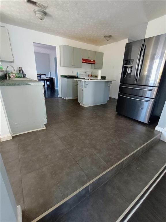 kitchen featuring sink, gray cabinetry, stainless steel fridge, a center island, and a textured ceiling