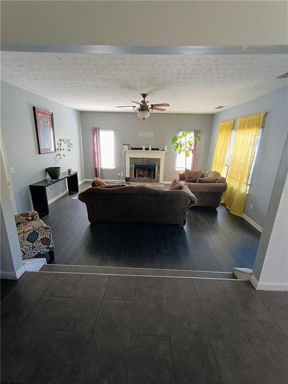 living room featuring ceiling fan, dark hardwood / wood-style flooring, and a textured ceiling