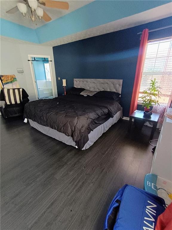 bedroom featuring dark wood-type flooring, ceiling fan, and a tray ceiling