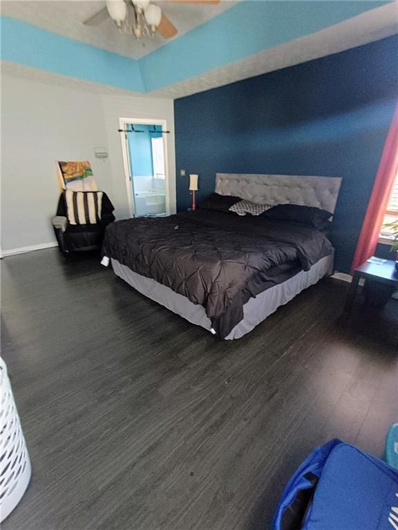 bedroom featuring ceiling fan, a tray ceiling, and dark hardwood / wood-style flooring