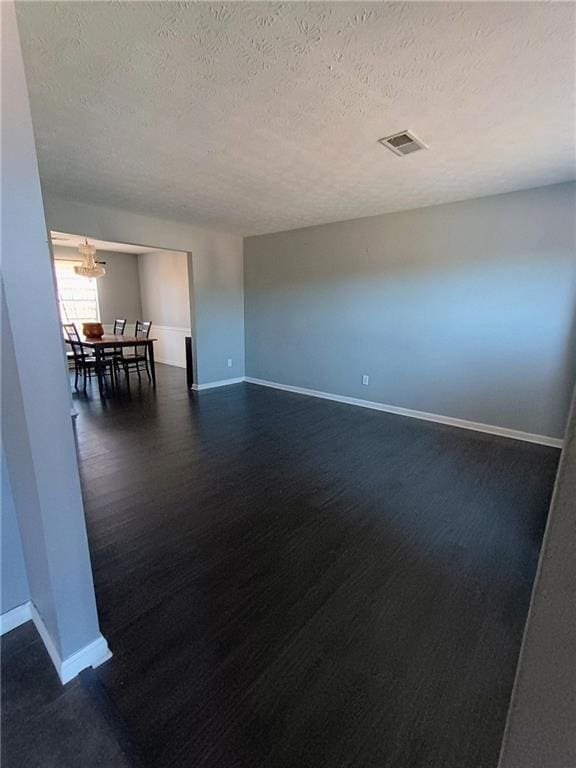 spare room featuring dark wood-type flooring and a textured ceiling