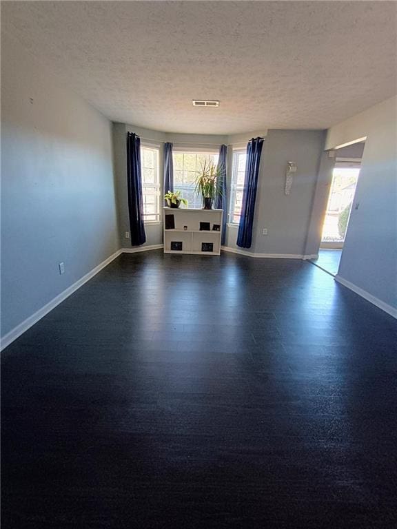 spare room featuring dark hardwood / wood-style flooring and a textured ceiling