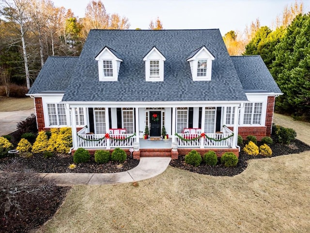 new england style home with a front yard and covered porch