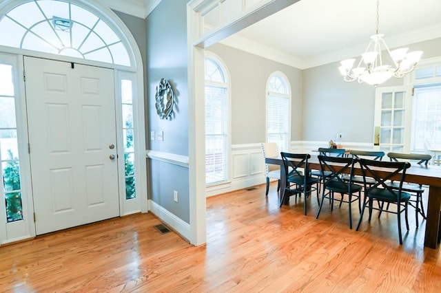 entrance foyer with crown molding, light hardwood / wood-style flooring, and a chandelier