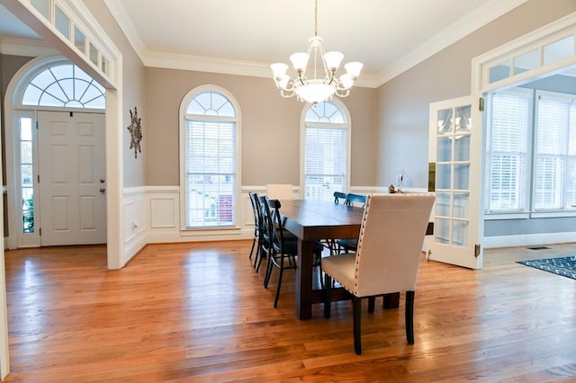 dining area with a notable chandelier, ornamental molding, a healthy amount of sunlight, and light wood-type flooring