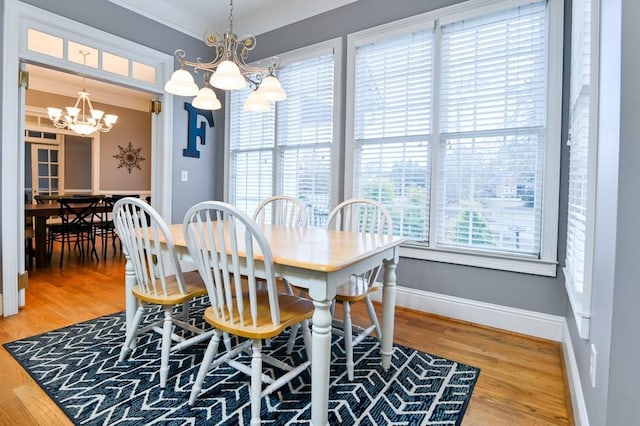 dining area with a notable chandelier, crown molding, and wood-type flooring