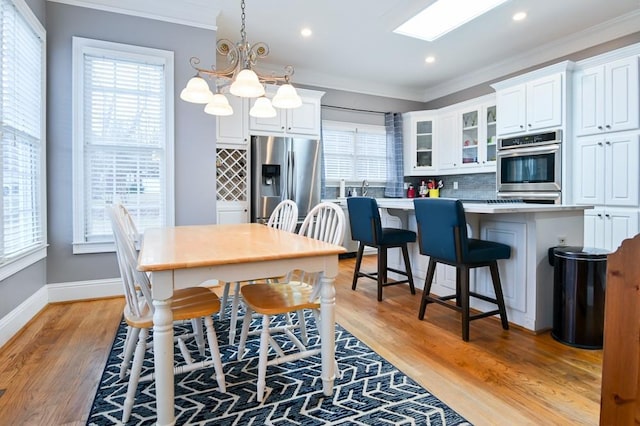 dining space with crown molding, a healthy amount of sunlight, and light wood-type flooring