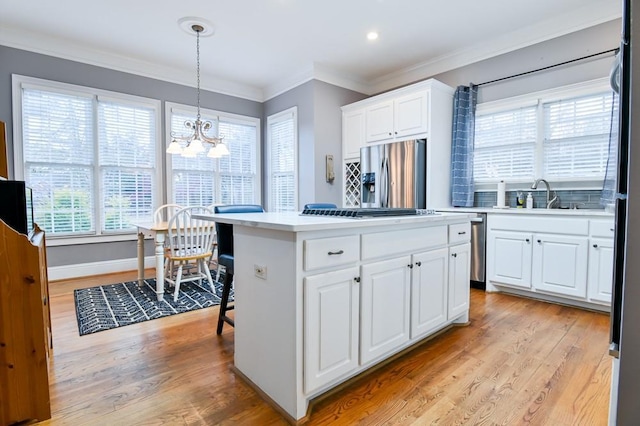 kitchen featuring stainless steel refrigerator with ice dispenser, sink, white cabinetry, a kitchen island, and pendant lighting