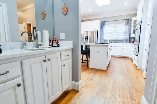 bathroom with sink, a skylight, ornamental molding, hardwood / wood-style flooring, and decorative backsplash