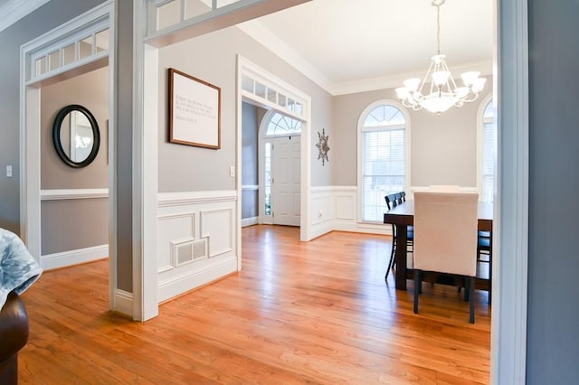 dining area featuring a notable chandelier, ornamental molding, and light wood-type flooring