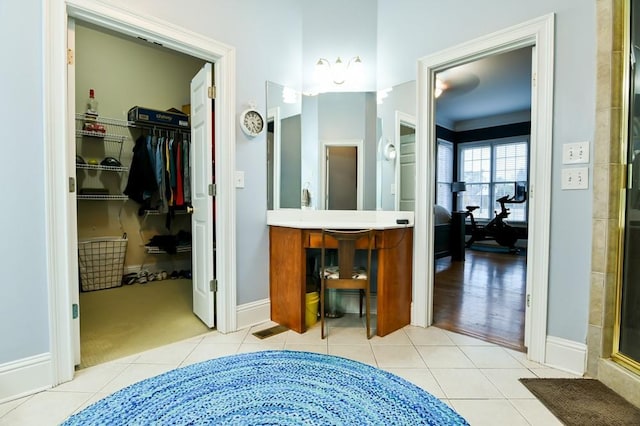 bathroom with a shower with door, vanity, and tile patterned flooring