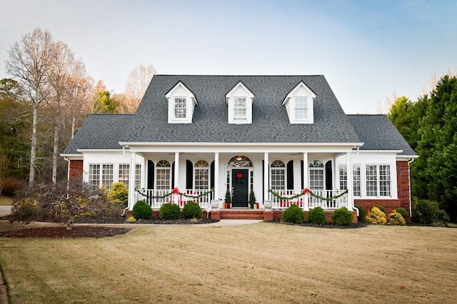 cape cod home featuring a front lawn and covered porch