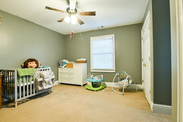 carpeted bedroom with a nursery area and ceiling fan