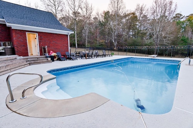 view of swimming pool featuring a patio and a diving board