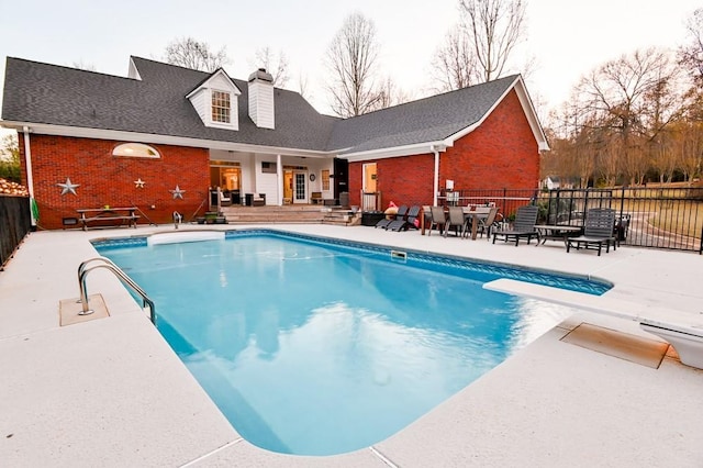 view of pool with a diving board and a patio area