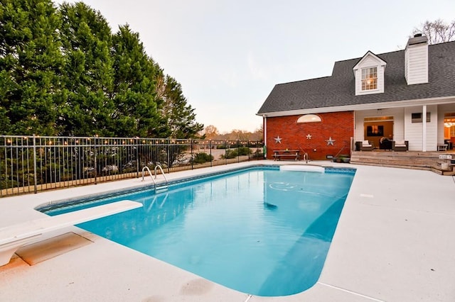 view of pool with a diving board and a patio area