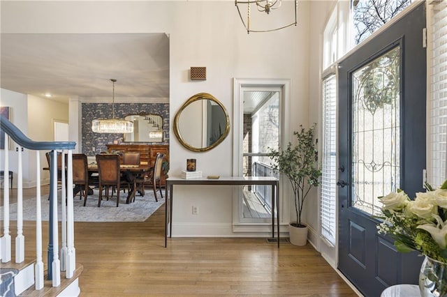 entrance foyer featuring visible vents, wood finished floors, baseboards, a chandelier, and stairs