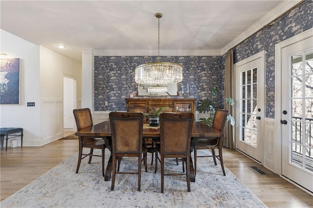 dining area with wainscoting, wallpapered walls, an inviting chandelier, and wood finished floors