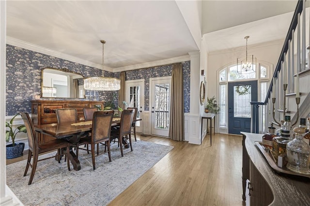 dining area with a notable chandelier, wainscoting, wallpapered walls, and crown molding