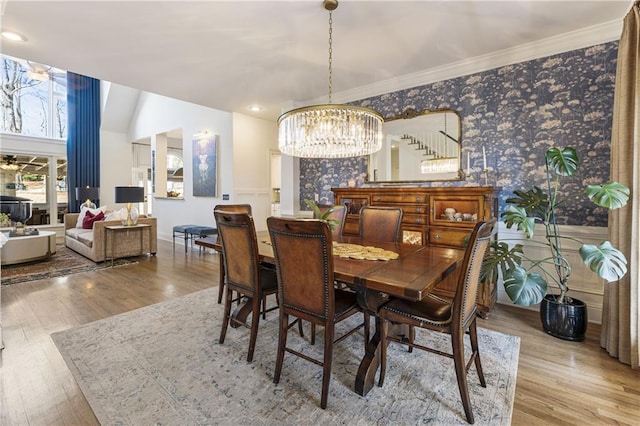 dining area with wallpapered walls, baseboards, ornamental molding, wood finished floors, and a notable chandelier