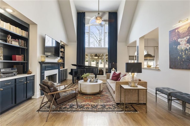 sitting room with light wood-type flooring, baseboards, and a towering ceiling