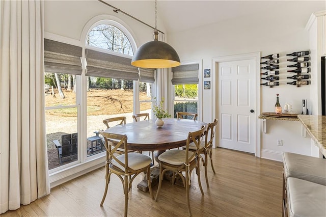 dining area with vaulted ceiling, light wood-style flooring, and baseboards