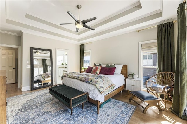 bedroom featuring light wood-type flooring, a raised ceiling, ceiling fan, and ornamental molding