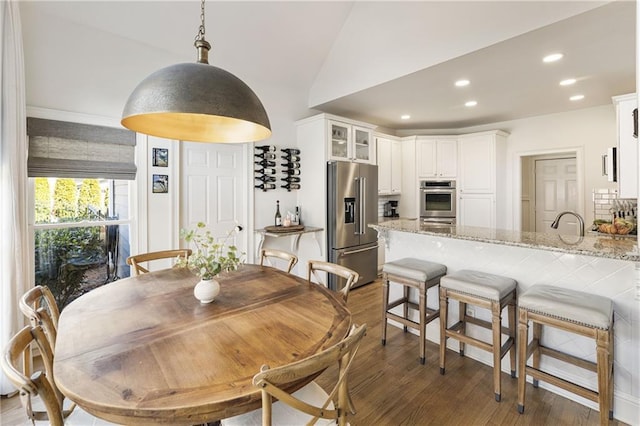 dining room with vaulted ceiling, recessed lighting, and wood finished floors