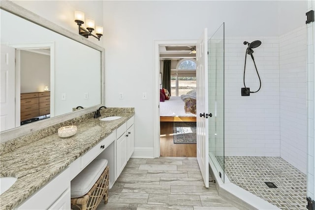 ensuite bathroom with a tile shower, connected bathroom, baseboards, ceiling fan, and vanity