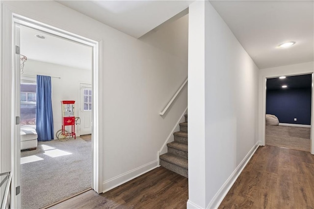 hallway with carpet floors, stairs, baseboards, and wood finished floors