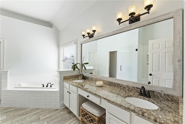 full bath featuring double vanity, lofted ceiling, a garden tub, and a sink