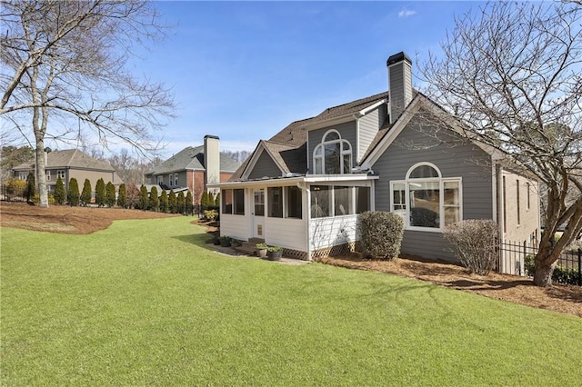 back of property with a chimney, fence, a yard, and a sunroom