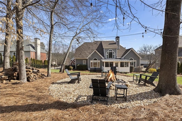 back of property with a chimney and an outdoor fire pit