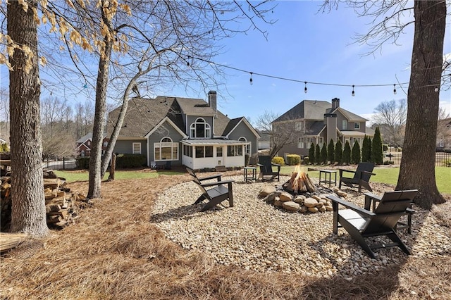 view of yard with a sunroom, fence, and an outdoor fire pit