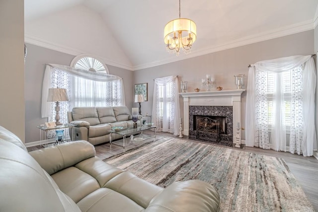 living room with a high end fireplace, crown molding, light hardwood / wood-style flooring, vaulted ceiling, and a chandelier