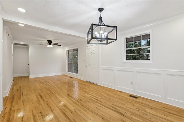 interior space featuring a decorative wall, ceiling fan with notable chandelier, light wood-style floors, and ornamental molding