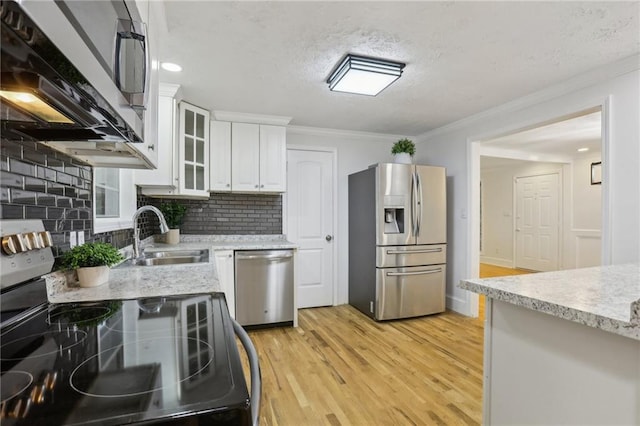 kitchen featuring tasteful backsplash, light wood-type flooring, ornamental molding, appliances with stainless steel finishes, and a sink