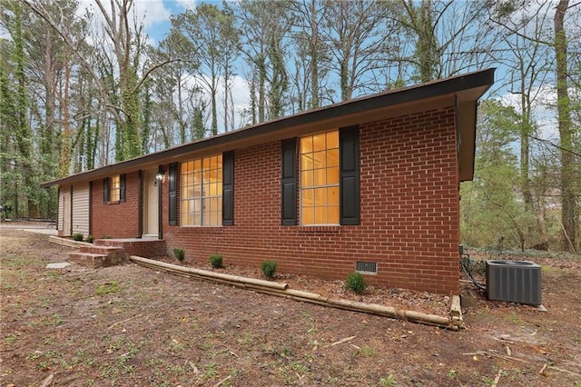 view of front of home featuring crawl space, brick siding, and central AC